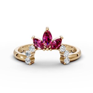 May include: A gold ring featuring a marquise-shaped ruby centre stone with smaller ruby stones flanking it. The band is set with smaller round diamonds.