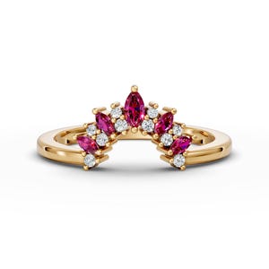 May include: A gold band ring with a curved design featuring a row of marquise-shaped pink gemstones and smaller round white gemstones.