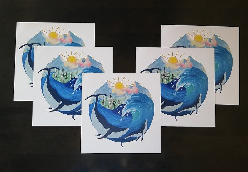 May include: Five white cards with a watercolor illustration of a whale jumping out of the water with a mountain range and sun in the background. The whale is blue and the water is a light blue with white foam.