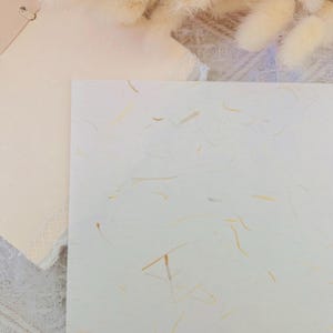 以下が含まれることがあります： 全体に小さな薄い淡い茶色の繊維が埋め込まれた白い質感の紙