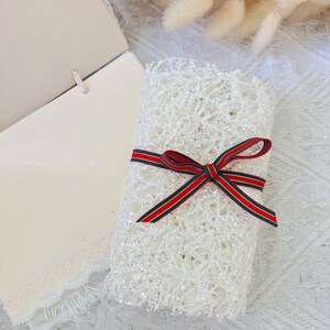 May include: A white lace-wrapped gift box with a red and green striped ribbon bow.
