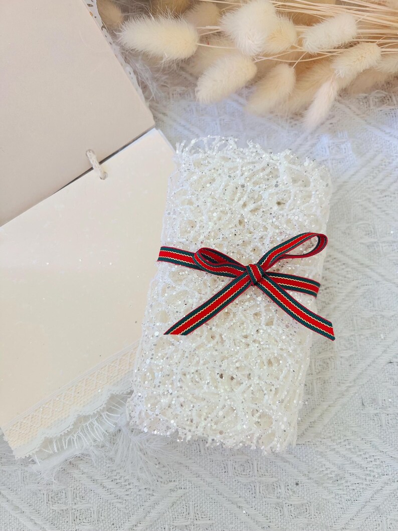 May include: A white lace-wrapped gift box with a red and green striped ribbon bow.