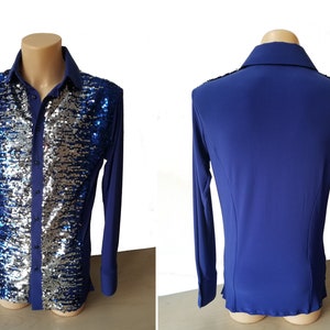 Puede incluir: Una camisa azul de manga larga con un diseño de lentejuelas plateadas y azules en la parte delantera. La camisa tiene un cierre de botones en la parte delantera y un cuello.