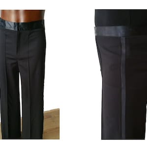 Op de afbeelding: Zwarte formele broek met een satijnen streep langs de zijnaden. De broek heeft een brede tailleband met een satijnen afwerking.