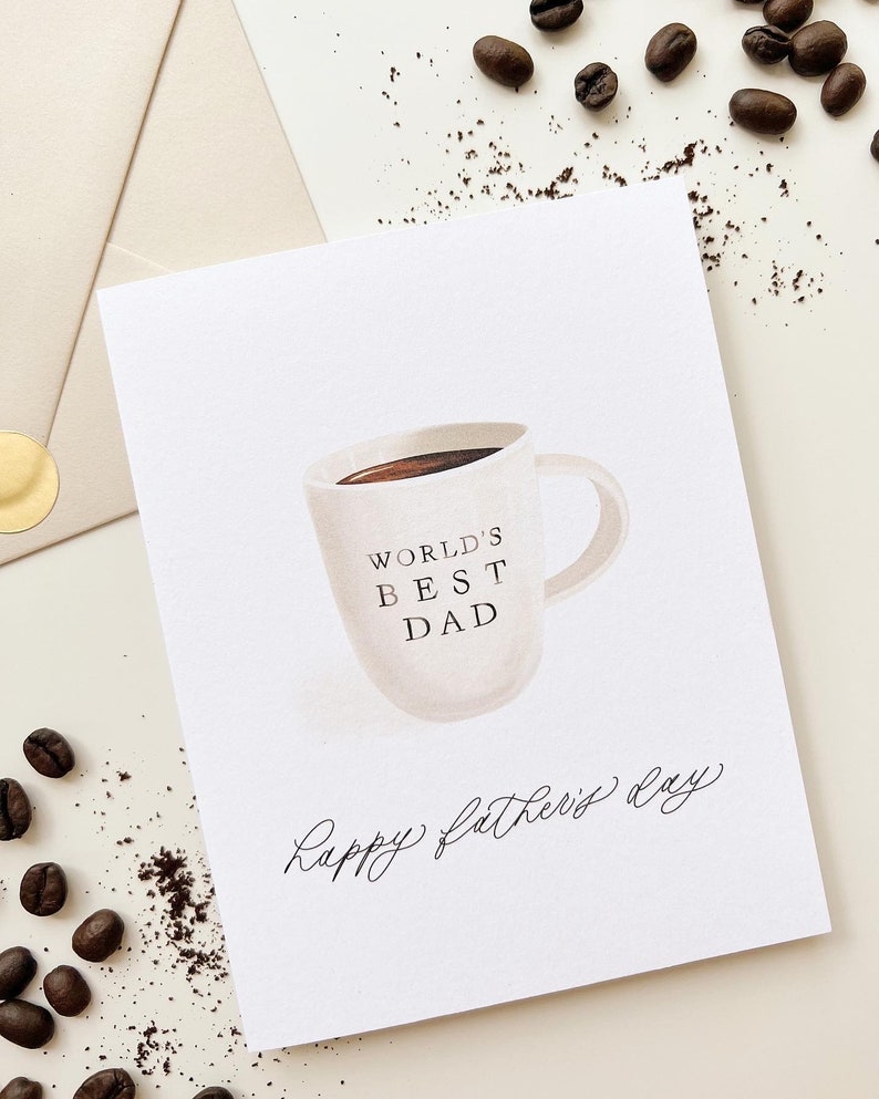May include: A white card with a coffee cup illustration and the text "World's Best Dad" on the cup. The card also has the text "Happy Father's Day" written in cursive.