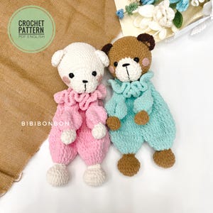 Puede incluir: Dos ositos de peluche de crochet. Uno es rosa y el otro azul claro. Ambos tienen ojos y narices marrones.