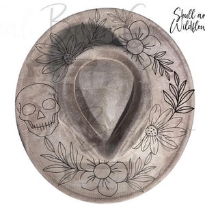 May include: A gray fedora hat with a skull and floral design. The hat features a skull on the left side and is adorned with black line art flowers and leaves around the brim. The text "Skull and Wildflowers" is on the right side.