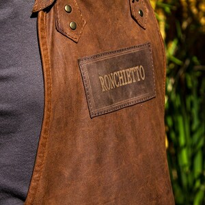May include: A brown leather apron with a patch that says "Ronchietto" on it.