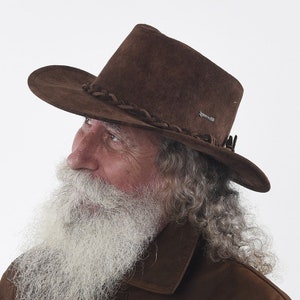 Può includere: Un cappello da cowboy in pelle scamosciata marrone con una fascia in pelle intrecciata e un piccolo logo sul lato.