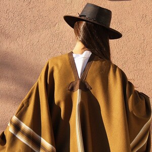 May include: A brown poncho with white and brown stripes. The poncho is worn by a person wearing a brown hat.