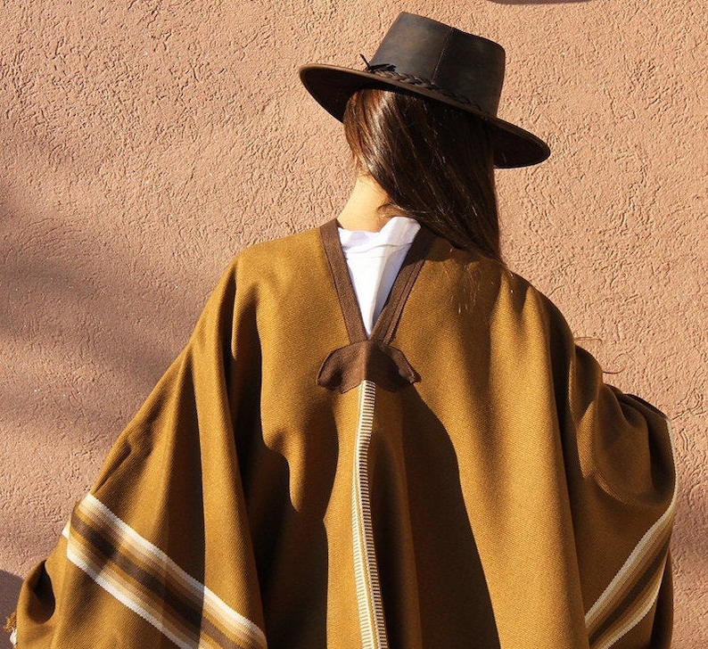 May include: A brown poncho with white and brown stripes. The poncho is worn by a person wearing a brown hat.
