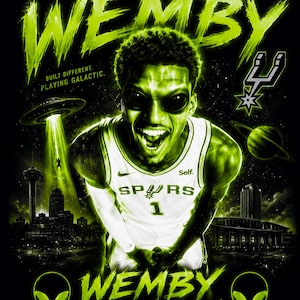 May include: A graphic print featuring a basketball player in a white Spurs jersey with the text WEMBY, NOT FROM HERE, BUILT DIFFERENT, PLAYING GALACTIC, WEMBY THE ALIEN, and SAN ANTONIO SPURS. The design includes a UFO, a planet, and alien faces in neon green.