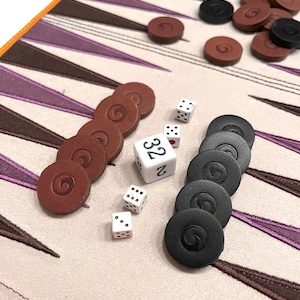 Backgammon dice and checkers displayed on the board’s suede surface. A quality backgammon game that makes an elegant and thoughtful gift.