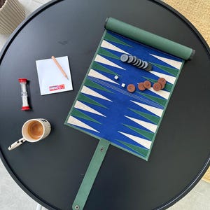 Open leather backgammon board with stitched triangles and checkers neatly placed, photographed on a rustic wooden surface. A quality boardgame ideal as a house present or luxury gift.