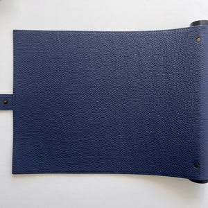 May include: A dark blue leather roll-up mat with a strap and metal rivets. The mat is rolled up and secured with a black strap.