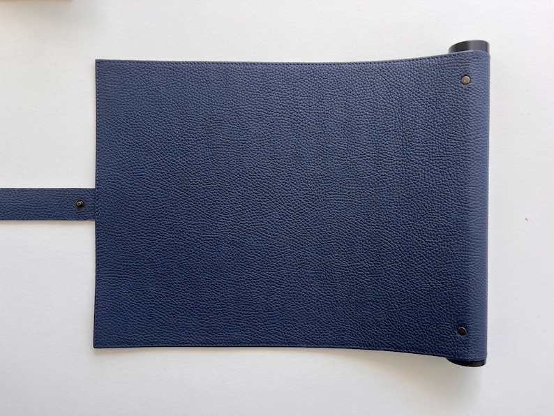 May include: A dark blue leather roll-up mat with a strap and metal rivets. The mat is rolled up and secured with a black strap.