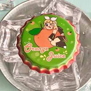 Puede incluir: Un tap&oacute;n de botella verde con una ilustraci&oacute;n de dibujos animados de una ni&ntilde;a sosteniendo una naranja. El texto "Orange Juice" est&aacute; impreso en el tap&oacute;n.