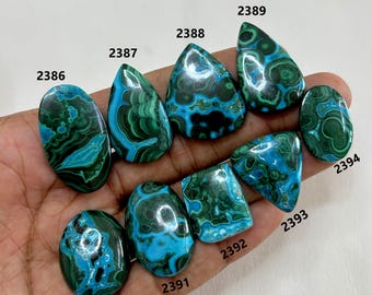 Könnte beinhalten: Eine Sammlung polierter Edelsteine in verschiedenen Formen, darunter oval, tropfenförmig und dreieckig. Die Steine weisen ein auffälliges Muster aus tiefen teal- und waldgrünen Wirbeln und Markierungen auf, mit individuellen Nummern.