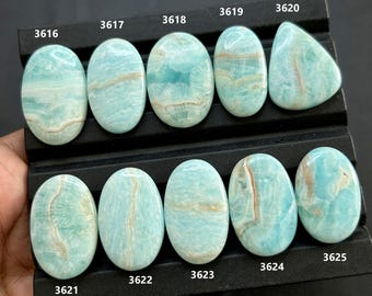 May include: A collection of ten polished Amazonite gemstones in various oval and teardrop shapes. The stones display a light blue-green color with brown and white veining. Each stone is labeled with a number.