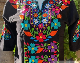 May include: Black embroidered blouse with colorful floral designs. The embroidery features flowers in shades of pink, red, orange, yellow, blue, green, and purple. The blouse has a V-neck and three-quarter sleeves.