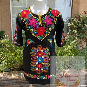 May include: Black embroidered dress with colorful floral designs. The dress has a round neckline and three-quarter sleeves. The embroidery features a variety of colors, including red, pink, blue, yellow, green, and white.