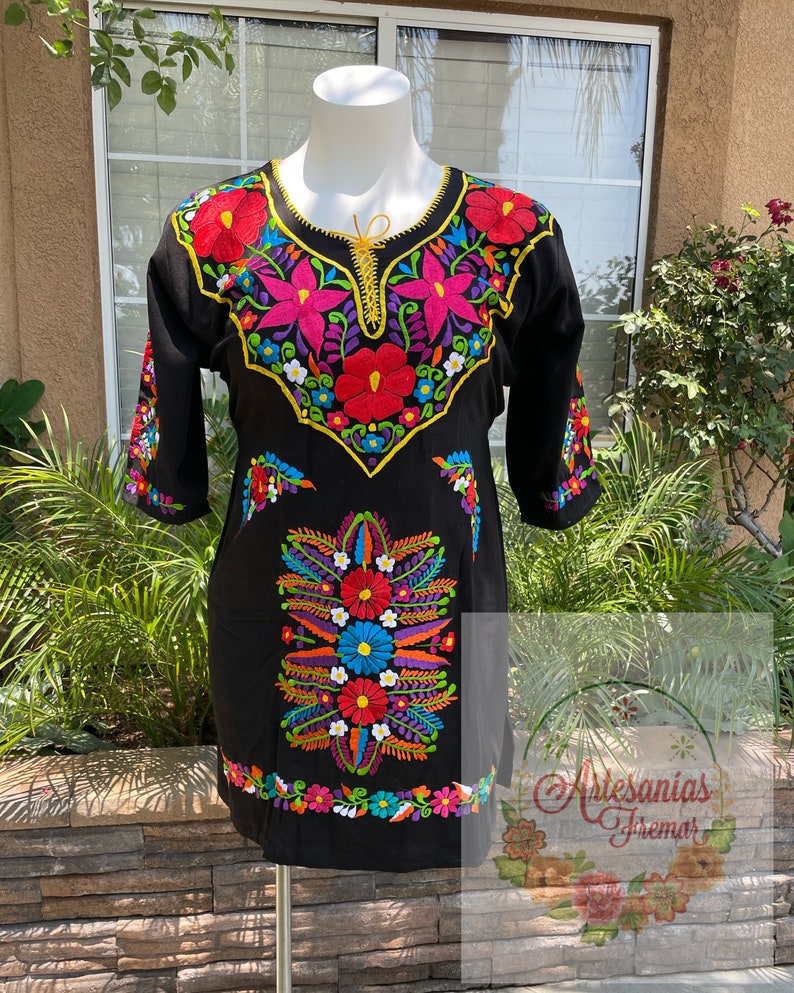May include: Black embroidered dress with colorful floral designs. The dress has a round neckline and three-quarter sleeves. The embroidery features a variety of colors, including red, pink, blue, yellow, green, and white.