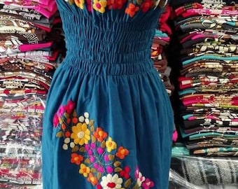 May include: A teal blue off-the-shoulder dress with colorful floral embroidery. The dress has a fitted bodice and a flowing skirt.