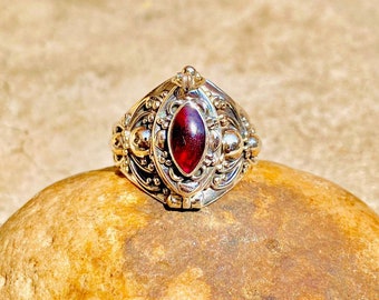May include: A silver ring with an ornate design and a red gemstone in the center.