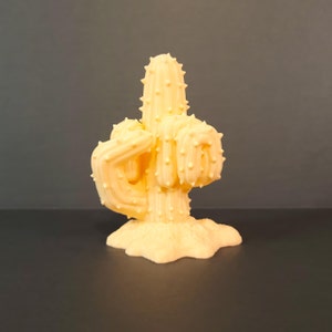 May include: A yellow 3D printed cactus shaped like a middle finger.