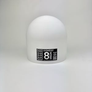 May include: A white 8 inch dome drape mold by Moon Ceramics. The object is a smooth, semi-spherical tool with a flat base. A black label on the front displays the text Moon Ceramics, Dome Drape Mold, 8 Inch, and includes a QR code for tool info.