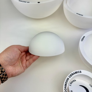 May include: A collection of white ceramic dome-shaped molds from Moonmoon Ceramics, featuring various sizes labeled in inches, including 3 inches, 7 inches, and 10 inches, with some pieces showing metric measurements like 152mm and 203mm.