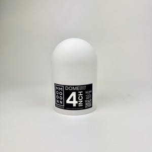Op de afbeelding: Een witte keramische dome-mal met een diameter van ongeveer 10 cm. Het product heeft een afgeronde bovenkant en een cilindrische basis. Het label luidt "MM Moon Ceramics" en "Drape Mold". Inclusief een QR-code en de tekst "Scan Tool Info". Gemaakt in Detroit, Michigan.