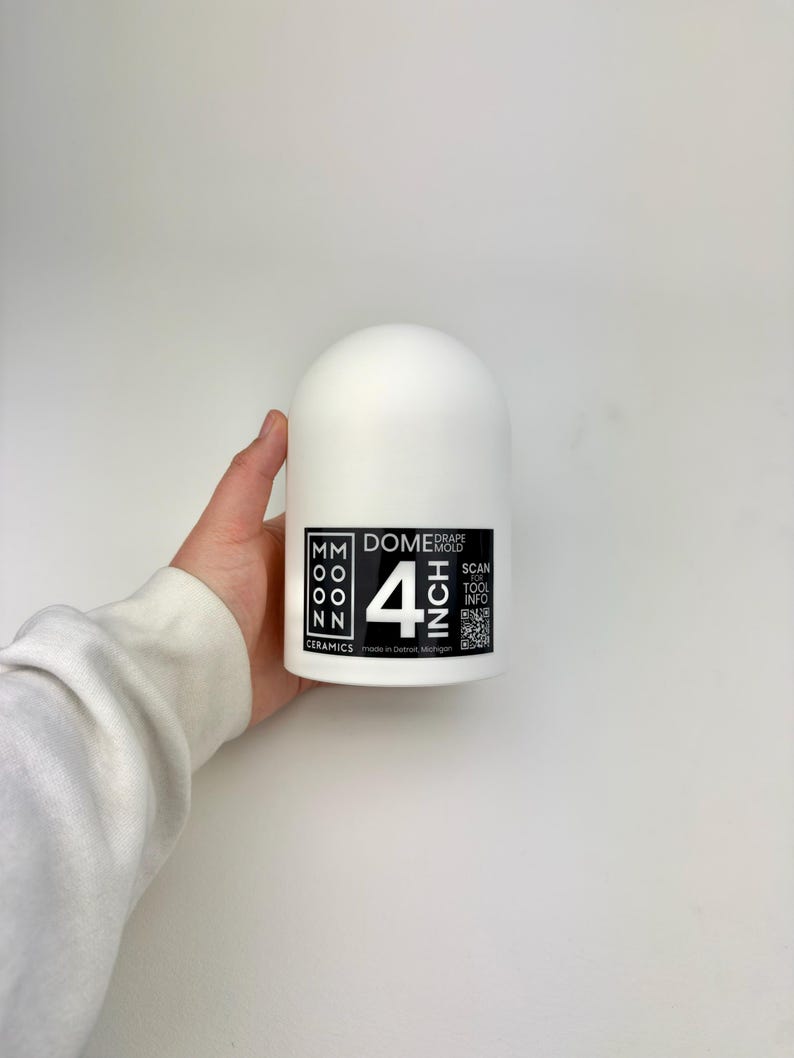 Op de afbeelding: Een wit keramisch koepelvormig object met een zwart-wit label met de tekst "4 INCH". Het label bevat ook de tekst "MM MOON NN CERAMICS" en "DOME MOLD". Het object wordt door een persoon vastgehouden.