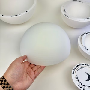May include: A collection of white ceramic bowls in various sizes, including a 10-inch bowl, a 7-inch bowl, and a 3-inch bowl. Each bowl features the text Moonmoon Ceramics printed along the rim, indicating specific measurements in inches.
