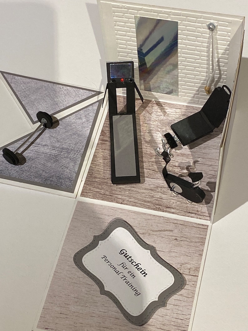 May include: A handmade papercraft gym scene with a treadmill, weight bench, and dumbbell. The interior features a mirror and a brick wall. A gift certificate with the text "Personal Training" is also included.