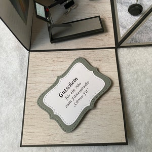May include: A handmade pop-up card with a gym theme. The card includes miniature gym equipment such as a weight bench, treadmill, and barbell. A decorative label reads "Gutschein f&uuml;r ein Abo zum Fitnessstudio 'Clever Fit'" in black text.