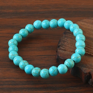 May include: A turquoise beaded bracelet with a simple design. The bracelet is made of round beads with a marbled pattern.