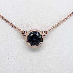 A lady&#39;s Minimalist 14k rose gold natural 0.95 carat Montana blue sapphire bezel pendant on chain.