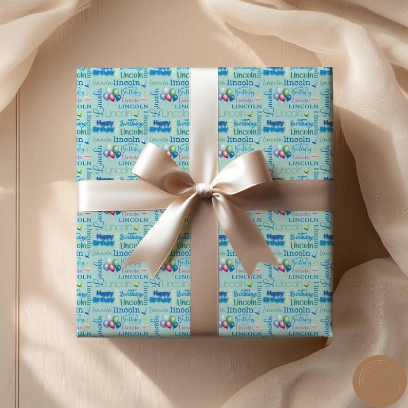 May include: A light blue gift wrap with a repeating pattern of the name "Lincoln" and the words "Happy Birthday".  The pattern also includes blue and pink balloons.  The gift wrap is tied with a beige ribbon.