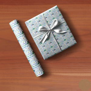 May include: A white gift wrap with a blue and green pattern featuring the name "Lincoln" repeated throughout. The wrap is tied with a white satin ribbon.