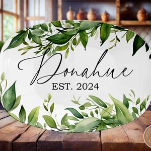 May include: White oval serving platter with a green leafy design around the edge. The platter has the text "Donahue EST. 2024" in black lettering.