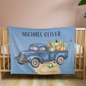 May include: A blue vintage pickup truck with a bed full of pumpkins. The truck is on a blue background with the name "Michael Oliver" printed above it.