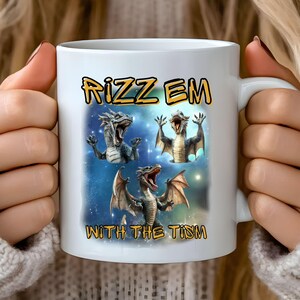 Puede incluir: Taza de cerámica blanca con un gráfico colorido de tres dragones y el texto "Rizz Em With The Tism".