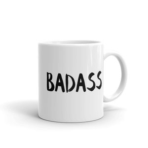 May include: White ceramic mug with the word "BADASS" printed in bold, black letters. The mug has a curved handle and a glossy finish, perfect for coffee, tea, or any beverage.