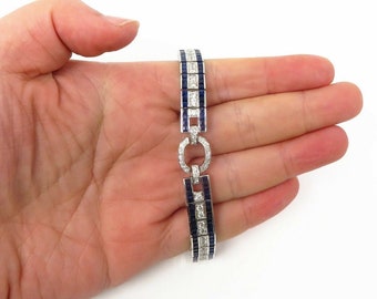 May include: A silver bracelet with a repeating pattern of alternating blue sapphires and diamonds. The bracelet has a circular clasp.