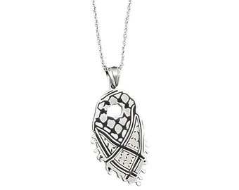 May include: A silver chain necklace with a pendant shaped like a traditional Middle Eastern headscarf. The pendant has a detailed design with a small hole in the center.