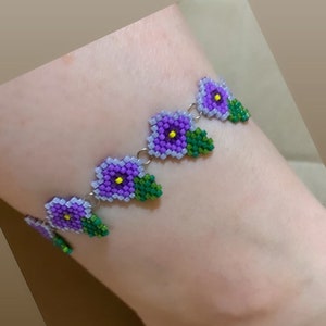 May include: Purple and green beaded flower anklet with a silver chain.