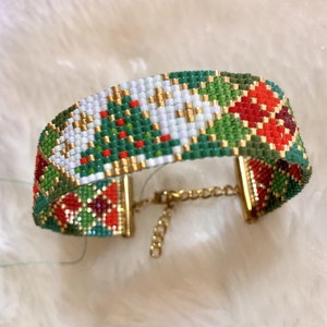 Puede incluir: Un brazalete de cuentas con un diseño de árbol de Navidad y flor de pascua. El brazalete está hecho con cuentas rojas, verdes, blancas y doradas. Tiene un cierre dorado.