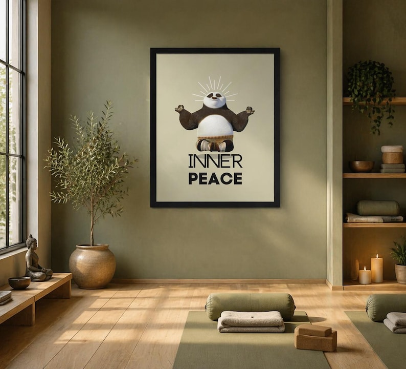 K&ouml;nnte beinhalten: Ein gerahmter Druck mit einem Cartoon-Panda in einer Yoga-Pose mit den Worten "INNER PEACE" in fetten, schwarzen Buchstaben. Der Panda hat einen wei&szlig;en Bauch, braune Arme und einen schwarz-wei&szlig;en Kopf. Der Druck befindet sich in einem Raum mit Yogamatten und einer Topfpflanze.