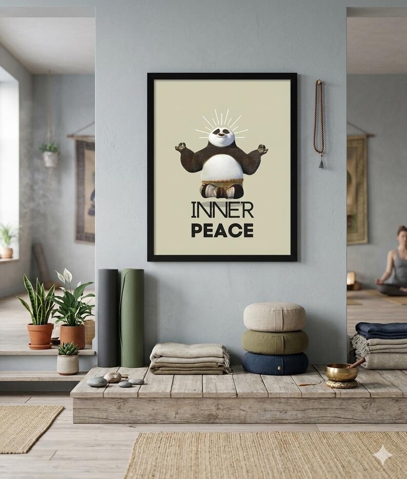 K&ouml;nnte beinhalten: Ein gerahmter Druck mit schwarzem Rahmen, der einen Cartoon-Panda in einer Yoga-Pose mit den Worten "INNER PEACE" zeigt. Das Bild wird in einem Yoga-Studio-Setting mit Yogamatten, Kissen und Pflanzen angezeigt.